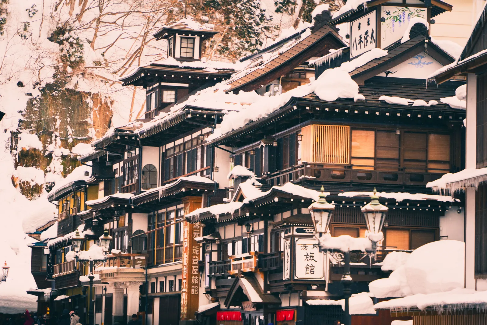 Wooden ryokan buildings lining the river at Ginzan Onsen with snow on the roofs