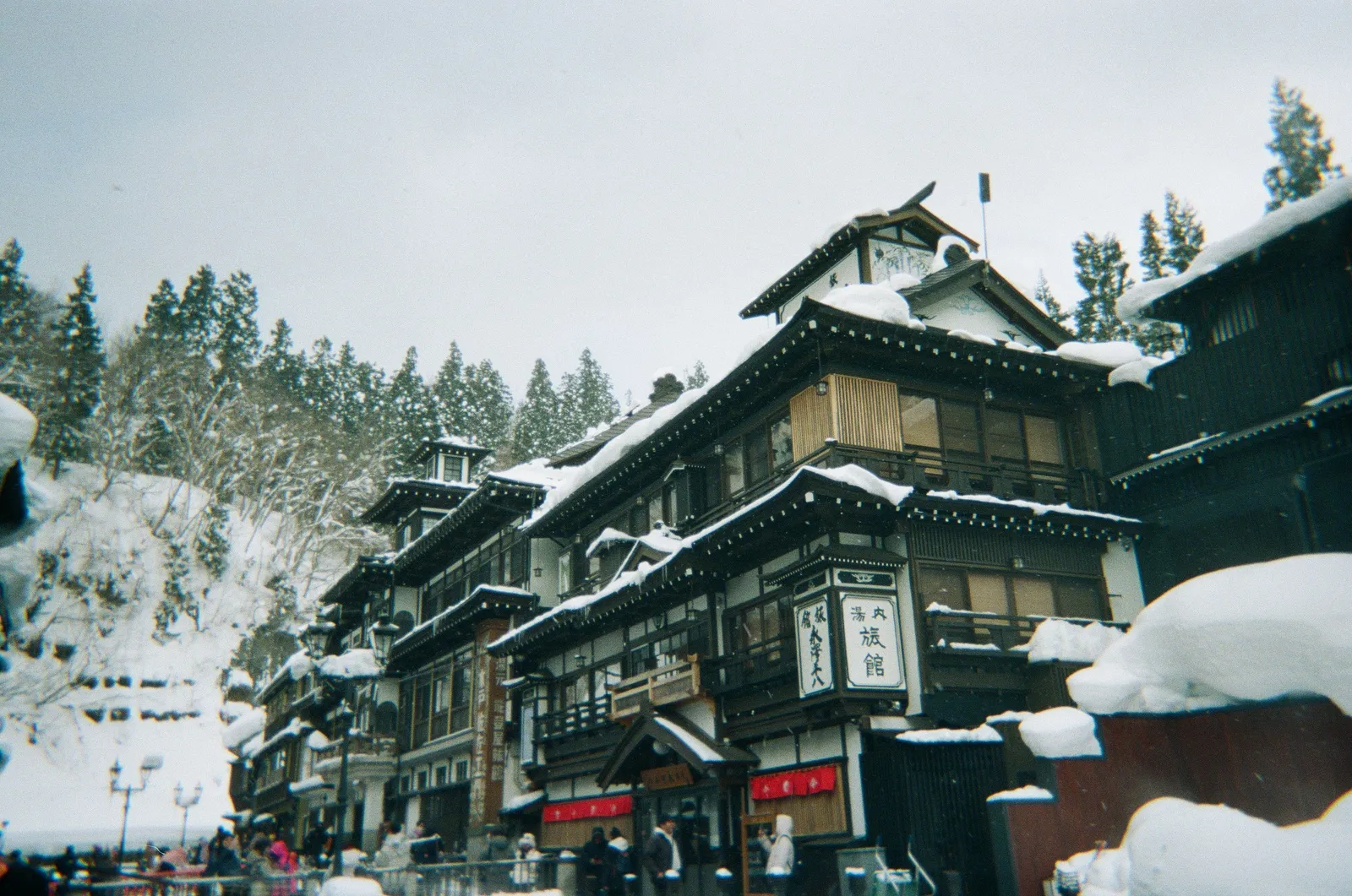 A snowy street of traditional wooden ryokan buildings in a Japanese hot spring town in winter