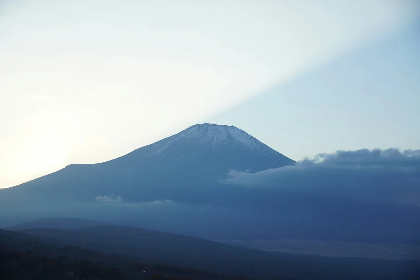 Mount Fuji's snow-capped summit rising above cloud, seen from a distance