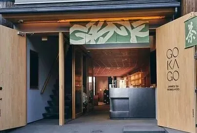 An open entrance with wide wooden doors, a green painted sign and a dark counter inside