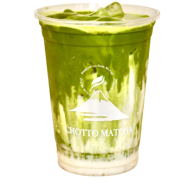 A tall plastic cup with a cold matcha drink in green and white layers