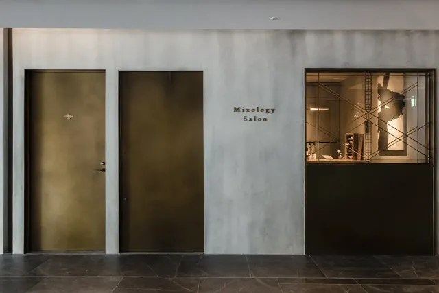 A concrete wall with two brass doors and a lit display window beside them