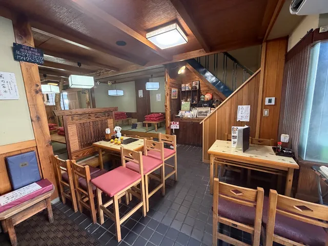 A dining room with wooden beams, wooden tables and chairs with pink cushions
