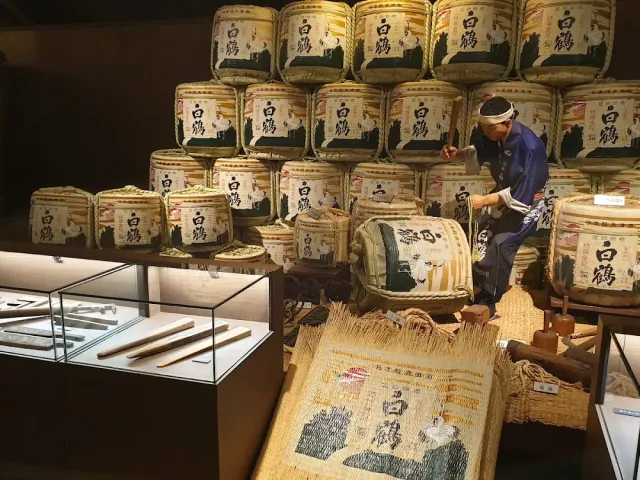 A stack of straw wrapped barrels with a worker mannequin in blue clothing and display cases