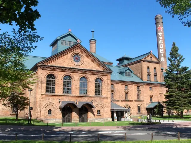 Red brick building with a tall chimney and a lawn in front
