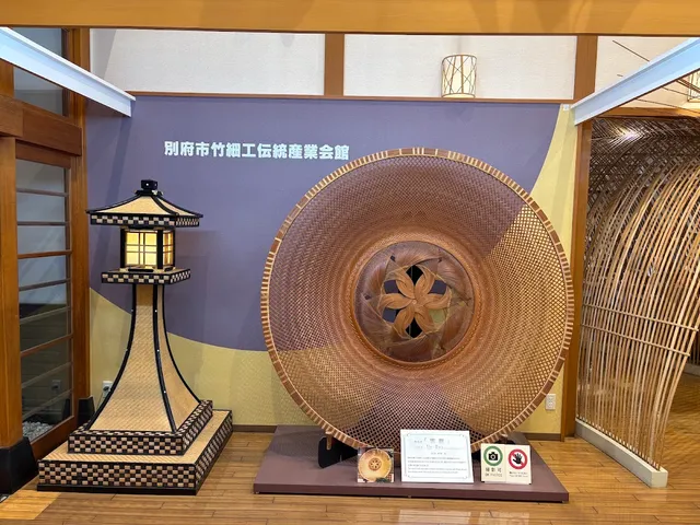 A giant woven bamboo basket and a bamboo lantern displayed in a hall with a wooden floor