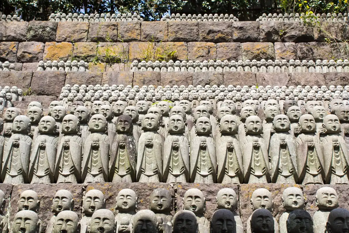 Dense rows of small stone statues on terraced steps among trees