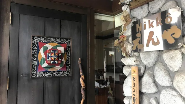 A dark wooden door with a colourful rug and a metal sign on a stone wall