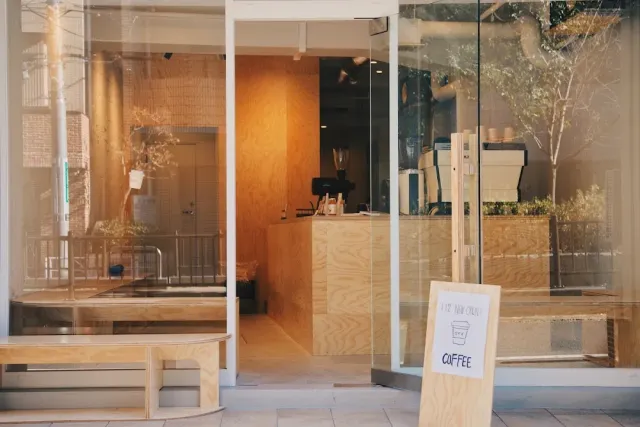 A glass front with a plywood counter, an espresso machine and a handwritten sign