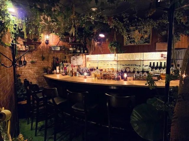 A curved bar with high chairs, brick walls and plants hanging from the ceiling