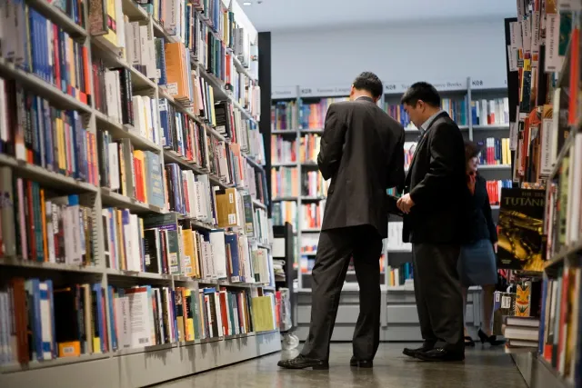 Two customers browsing tall bookshelves