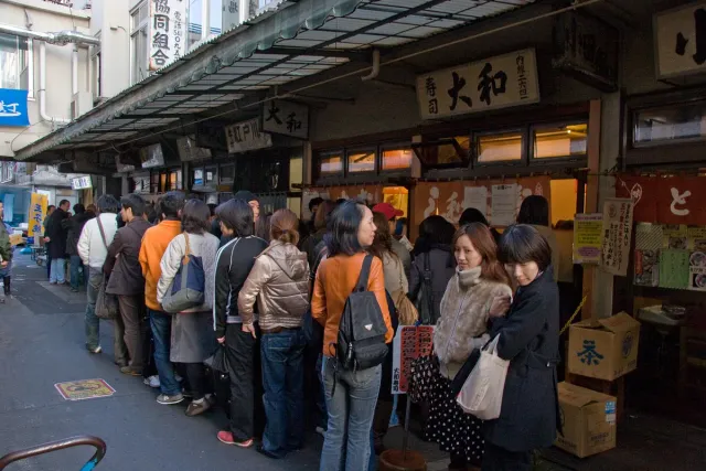 A long queue of people along a narrow market corridor
