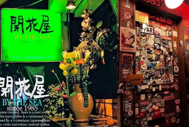A dim entrance with a lit green sign, a flower vase and a wall covered in stickers