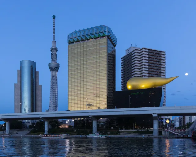 A tall observation tower behind a building topped by a golden sculpture