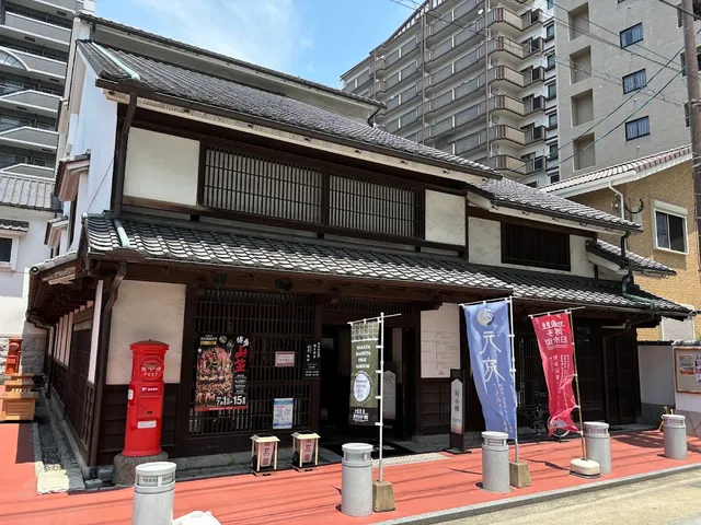 A traditional wooden house with a tiled roof, a red mailbox and colourful flags at the entrance