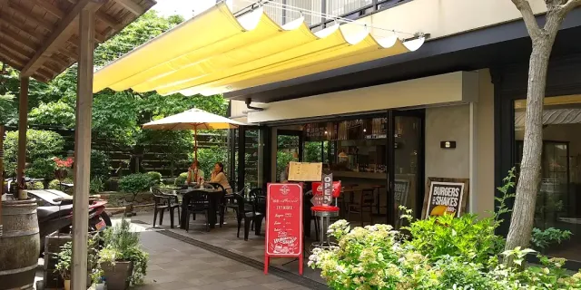 An outdoor terrace with yellow awnings, a parasol, chalkboards and a green garden around