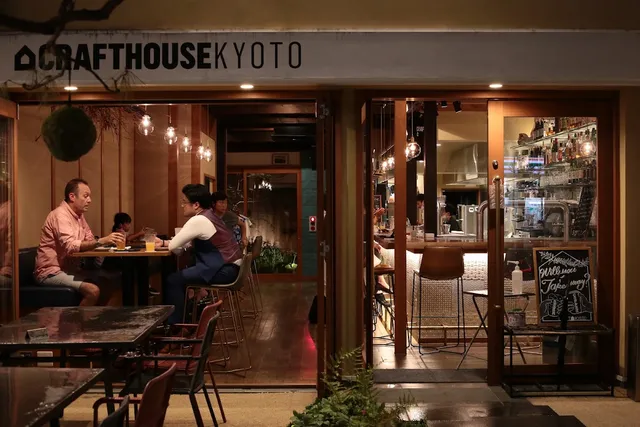 A glazed frontage in the evening with diners at tables and a lit bar behind