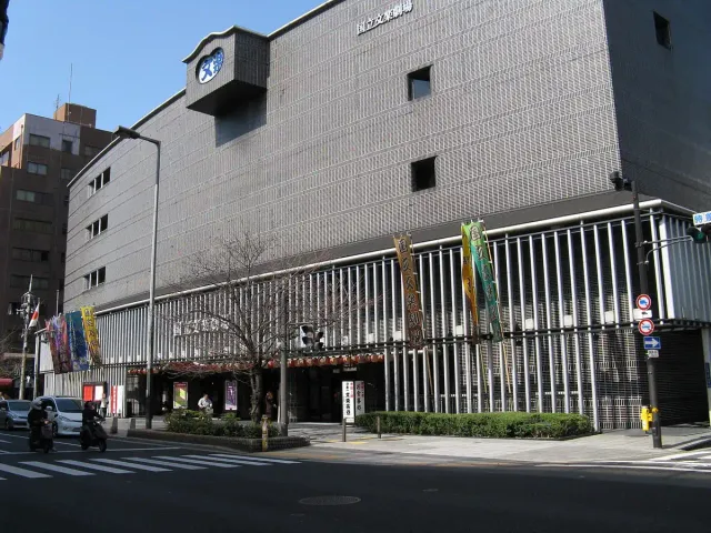 A modern grey theatre building with vertical banners