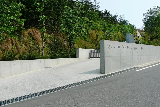 A bare concrete wall along a rising ramp, without windows