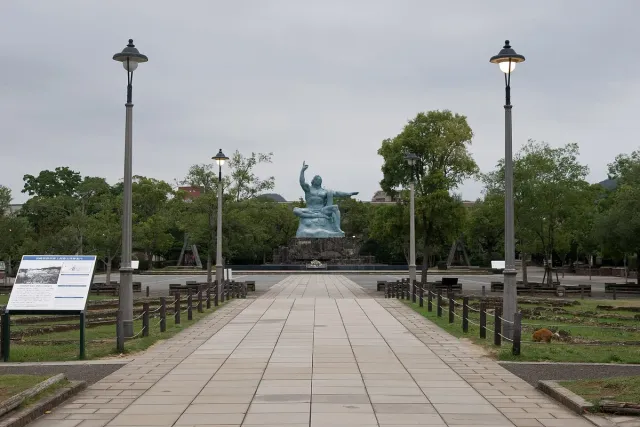 A wide plaza with lamp posts and a statue at the far end