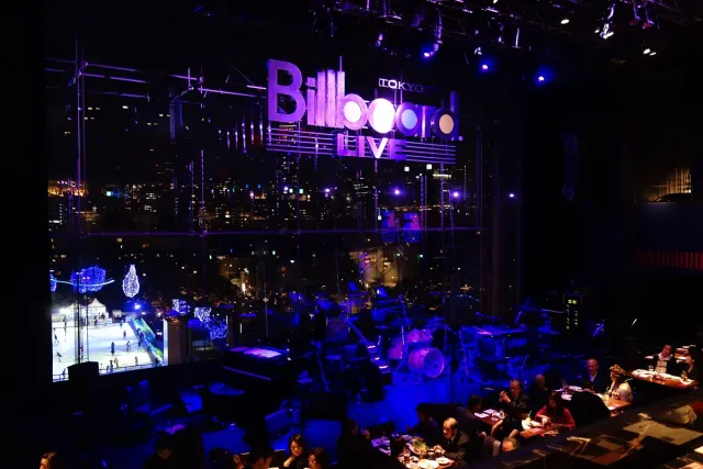 A live music room lit in blue with a stage and illuminated signage