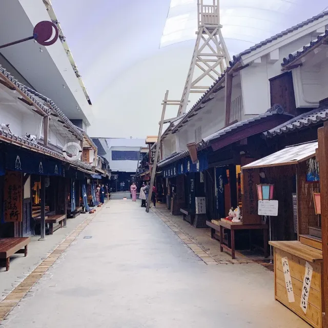 A reconstructed street inside a closed building, with wooden facades and a lit ceiling