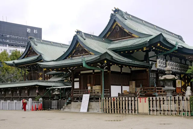 Shrine buildings with curved green roofs behind a fence