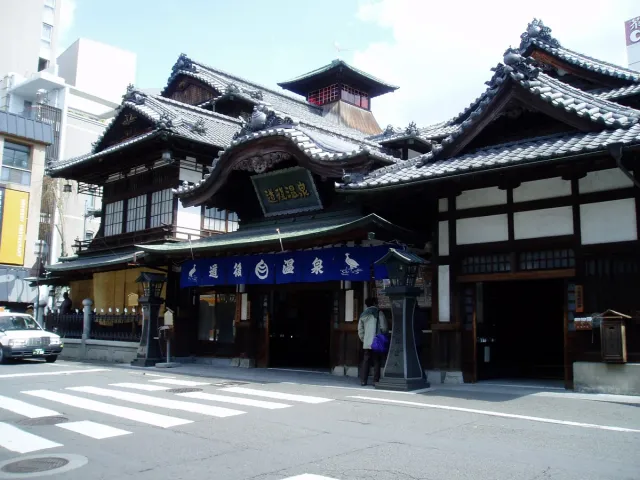 A multi-storey wooden building with dark tiled roofs on a street corner