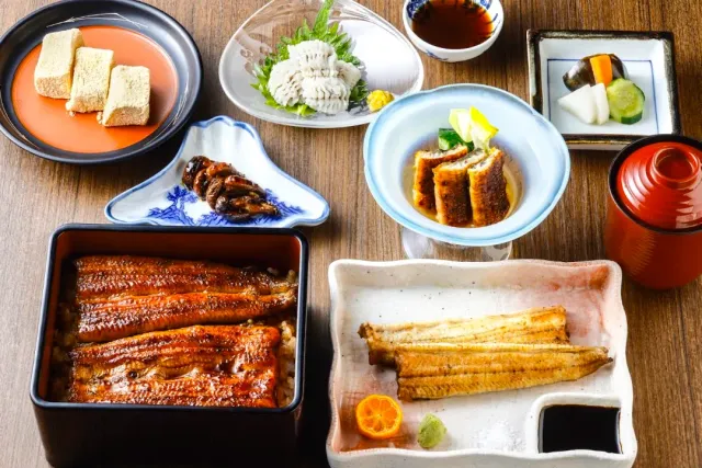 Grilled eel over rice in a lacquer box, beside white eel and small side dishes
