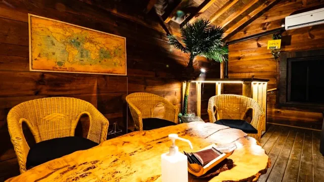 A wooden room with a live edge table, wicker armchairs and a world map on the wall