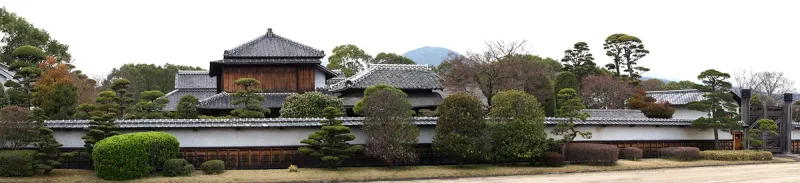 Restored samurai residence with a tiled roof and a clipped garden in front of it