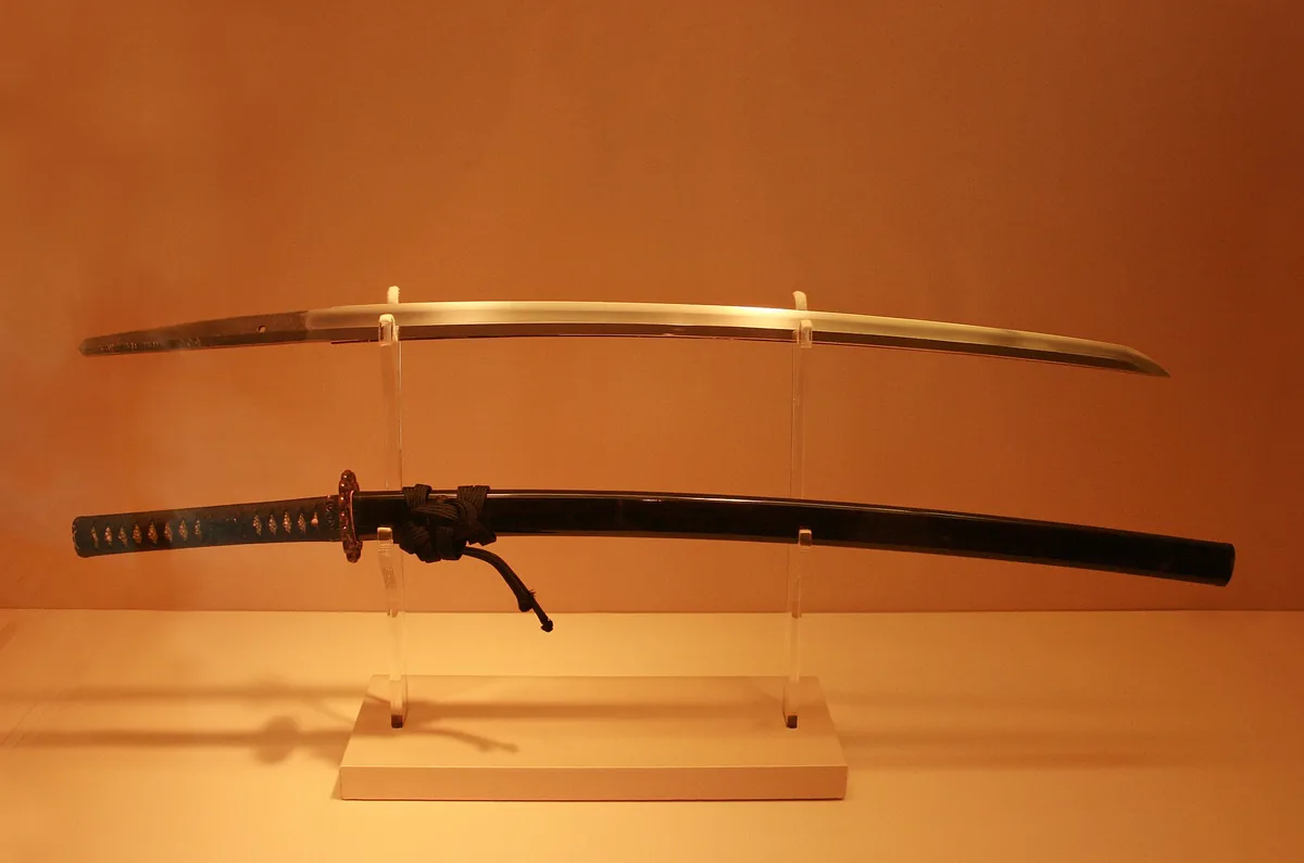 A katana and its black scabbard resting on a display stand