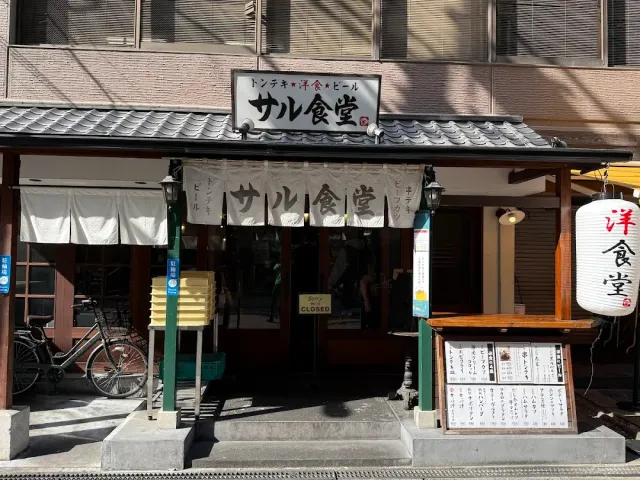 A facade with a tiled roof, a white cloth curtain, a paper lantern and a menu board