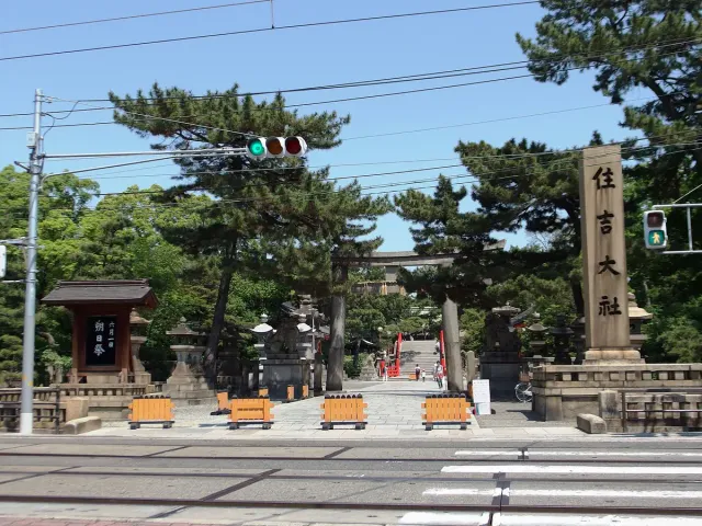 A stone gate and shaded entrance with benches and pine trees