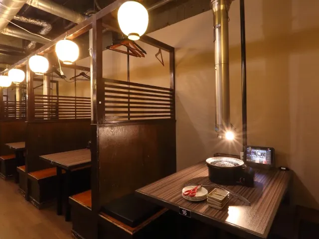 Seating booths with a grill sunk into the table, a brass duct and lit round lanterns
