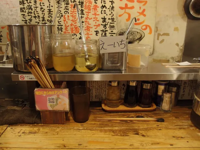 A narrow counter with condiment jars and a hand-written menu on the wall
