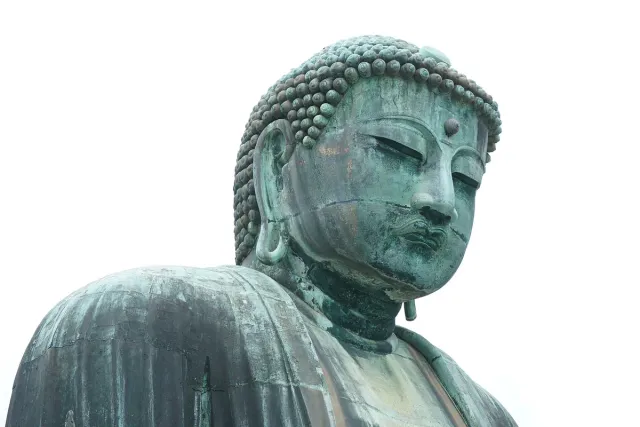 A giant bronze Buddha statue, weathered green, against the sky