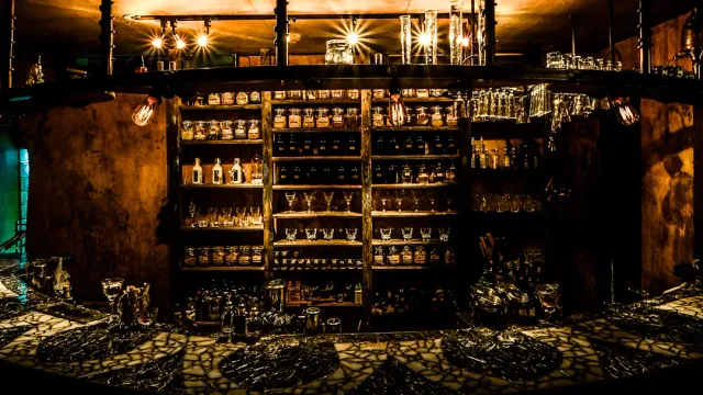 Wooden shelves loaded with bottles and glasses in golden light above a dark counter
