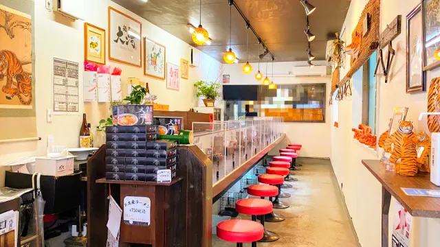 A narrow space with red stools along a counter, tiger pictures and tiger figurines on a shelf