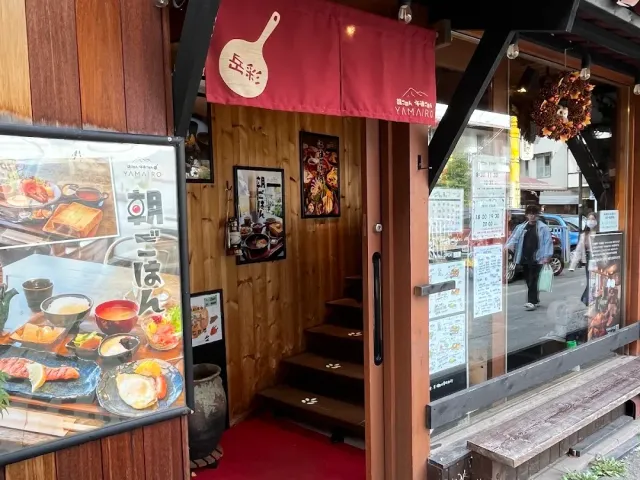 An entrance with a red awning, steps leading inside and a picture sign of a breakfast