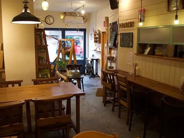 An interior with wooden tables, assorted chairs and a large black hanging lamp