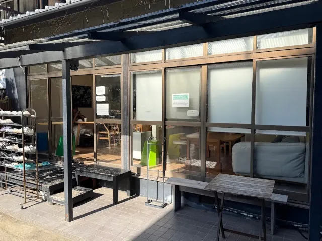 A dark facade with glass frames, a wooden bench and an open entrance to an inner room