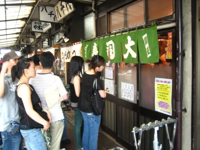 People queueing outside a sushi bar in a market