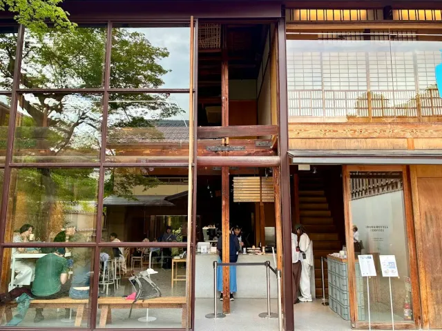 A two storey wooden house with a glass front, with guests seated at tables inside