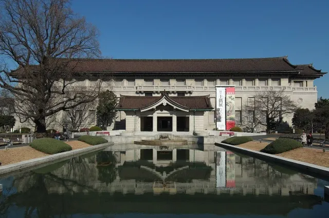A symmetrical museum building behind a rectangular pool