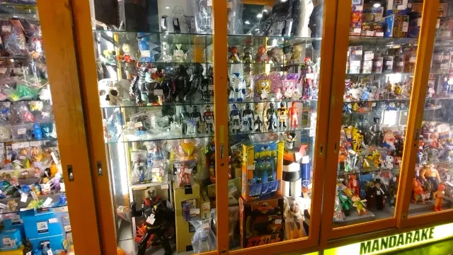 Glass cabinets packed with dolls and boxed figures, in a narrow shop aisle