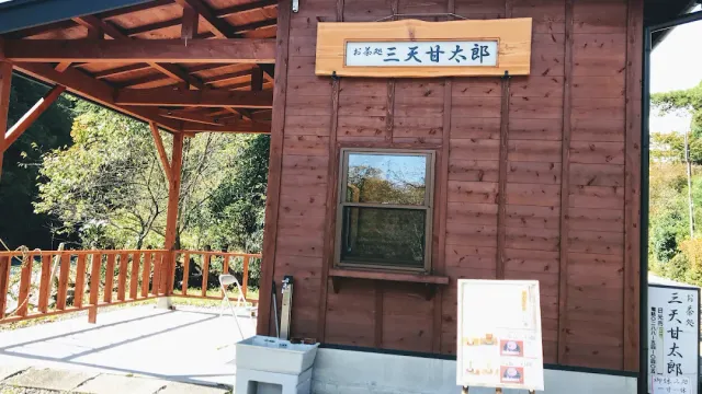 A reddish wooden building with a sign in Japanese, a small window and a covered terrace