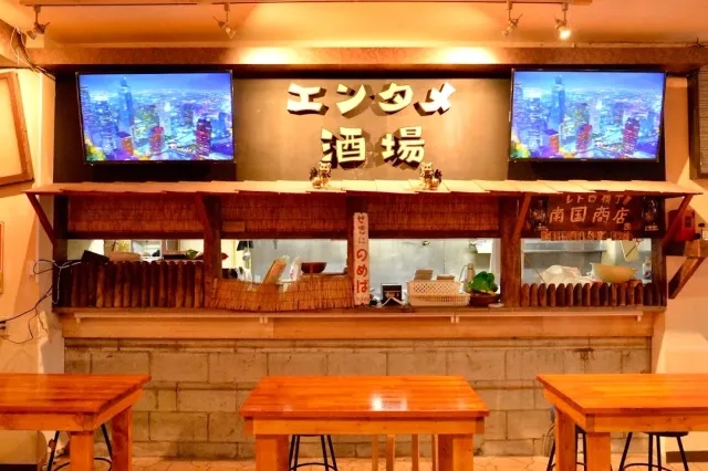 Two screens showing a city view above a kitchen counter, with wooden tables in front