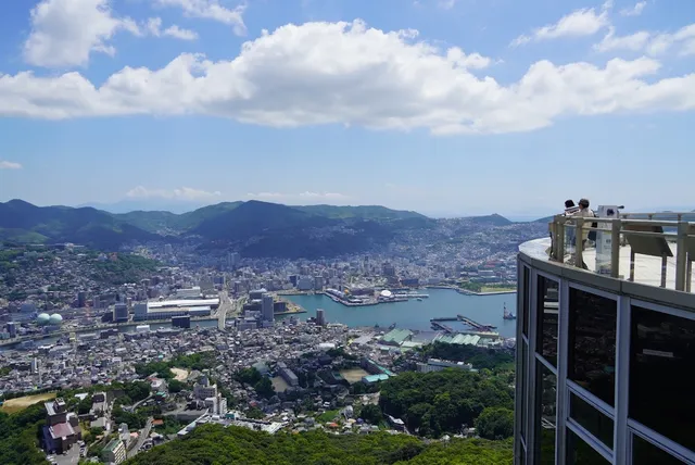 A port city around a blue bay seen from above, beside a glass observation deck