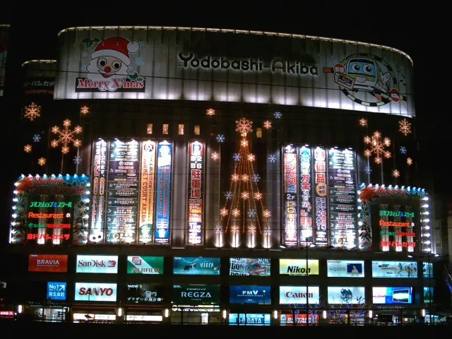 The front of a huge electronics store covered in illuminated brand signs